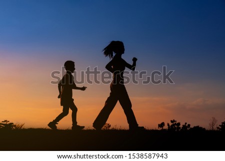 Silhouette woman and boy active walking, Freedom family mother son
 relax sport exercise at sky sunset
 background