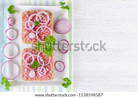 german sandwich mettbrotchen, bun and raw meat with onion and parsley, copy space