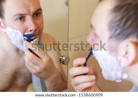 A man shaves in the bathroom in the morning before work