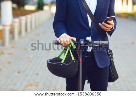 Young man in rides an electric scooter on a city street in summer Royalty-Free Stock Photo #1538606558