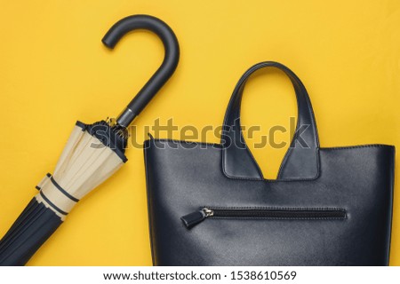 Leather bag, umbrella on yellow background. Minimalism fashion concept. Top view