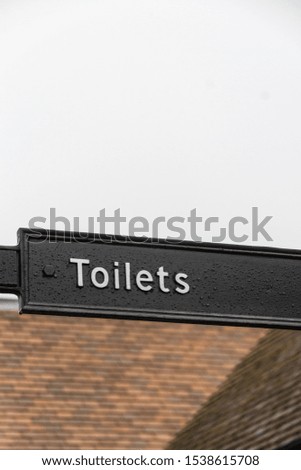 Pole with black sign, white writing for toilets, portrait