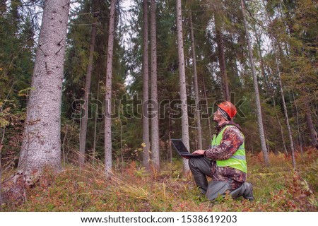 Forest engineer works in the forest with a computer. Forestry and computer technology.
