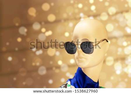 Mannequin head in sunglasses on a beige bokeh background. dummy model in a shop window of clothes and accessories, bald doll head