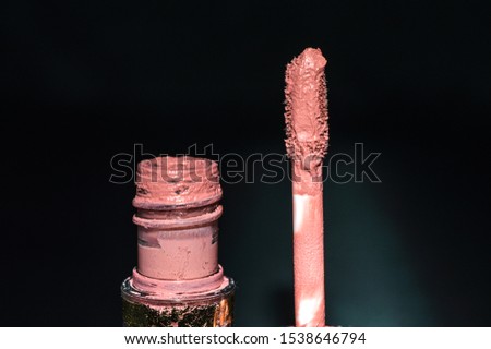 Brown lipstick tube with brush, black background. Close up photo.