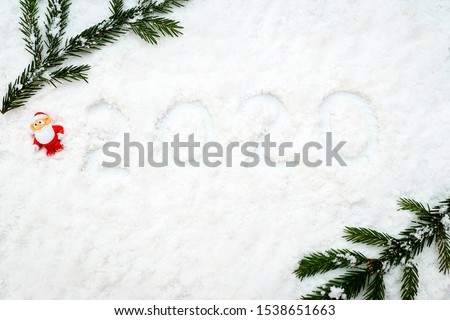 Christmas holiday decor with fir tree brunch and Santa Claus. New year decoration background on the artificial snow, flat lay, top view, horizontal, copy space