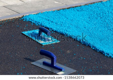 Rubber coating for playgrounds applied on the surface by a steel trowel. PDM rubber granules. Coating and floor covering for sports. Rubber mulch for safety and injury prevention. Selective focus. Royalty-Free Stock Photo #1538662073