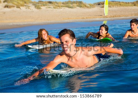 Teenager surfer group boys and girls swimming over the surfboard