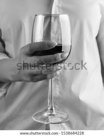The girl holds a glass in her hand. Red wine in a glass close-up.