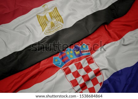 waving colorful flag of croatia and national flag of egypt . macro