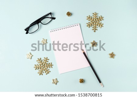 Notebook on blue background with christmas decor. Space for text. New year goals concept or greeting card concept.