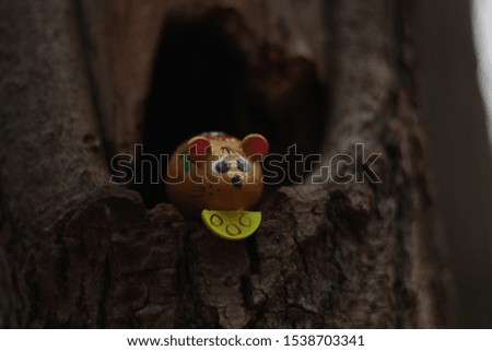 toy mouse with cheese sitting on a tree