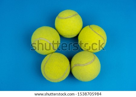 Green tennis balls in the shape of a star on a blue background, color contrast