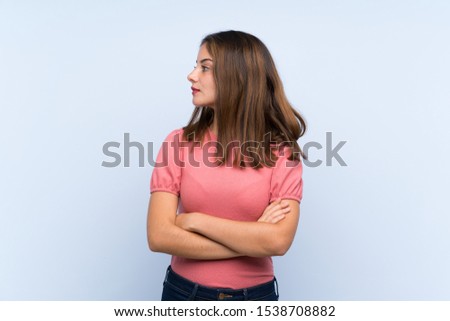 Young brunette girl over isolated blue background looking side