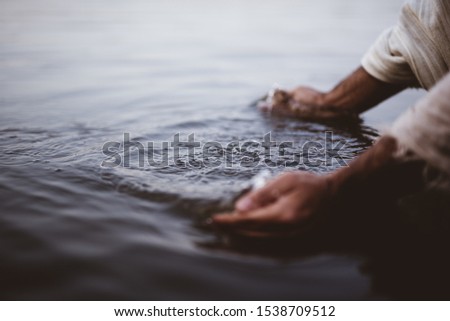 A closeup shot of a person wearing a biblical robe washing his hands in the water Royalty-Free Stock Photo #1538709512