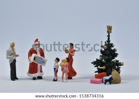 Santa claus in front of a christmas tree with a family with two children