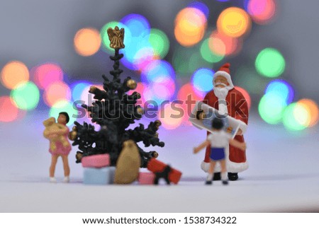 Santa claus in front of a christmas tree with a family with two children