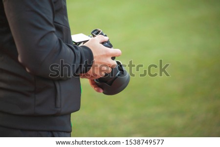 A man holds a camera in his hands on a blurry green background, a professional photographer makes pictures