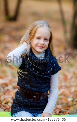 beautiful blonde girl in autumn park. looking at the picture and smiling