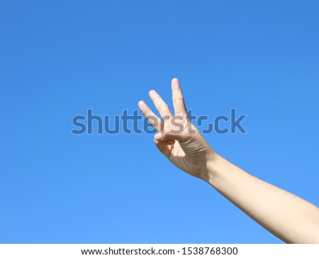 Three finger of woman hand on blue sky background