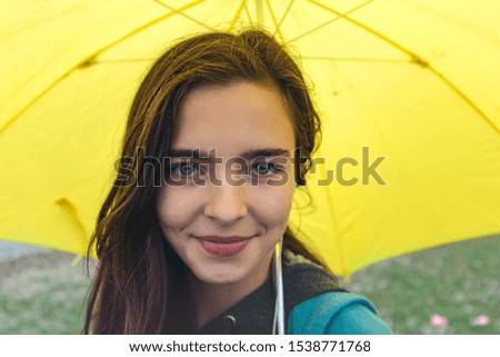 portrait of a smiling young woman with yellow umbrella