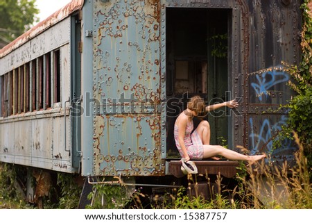 Young woman sitting in an abandoned train car.