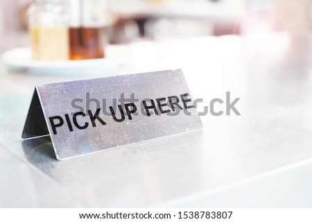 Metal Pick up sign on the white table in coffee shop     