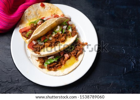 Traditional mexican quesadillas with shredded pork also called "chilorio" on dark background