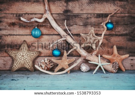 Beachy scene of starfish and teal ornaments for Christmas on a wooden background