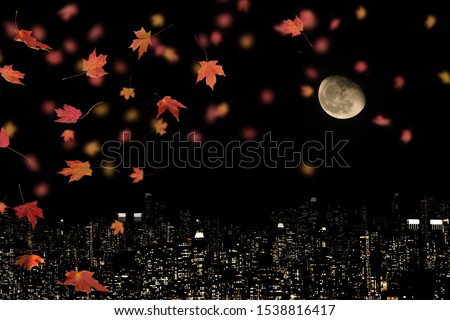 Falling autumn leaves at night with background of landscape of skyscrapers and the moon.