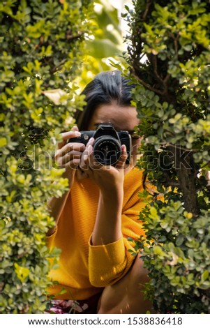 portrait of a woman taking photos with a camera in a forest