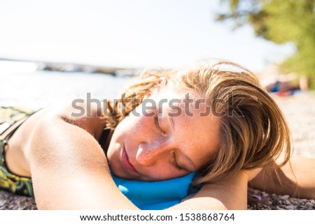 A woman is sunbathing on a beach. The girl in a bathing suit lies on the seashore. Holidays on the coast.