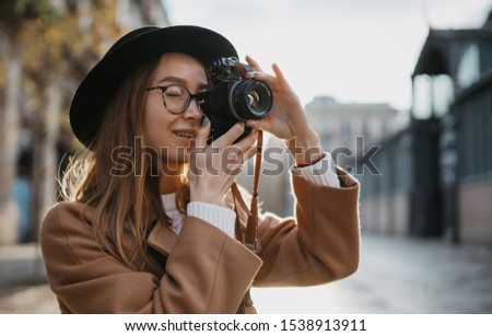 Photographer take photo on retro camera. Tourist portrait. Girl in hat travels in Barcelona holiday. Sunlight flare street in europe city. Traveler hipster shooting architecture, copy space mockup
