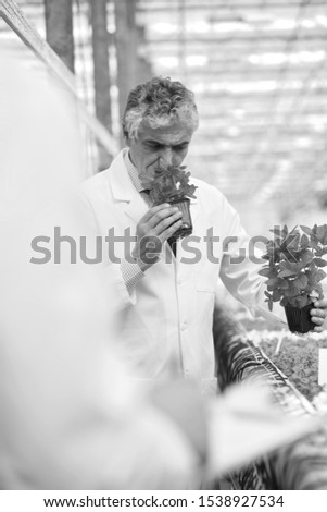 Black and white photo of Male botanist smelling herbs in plant nursery