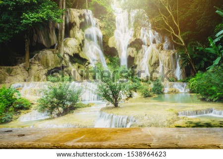 Waterfall in rain forest in west of Laos with orange sun light in background. Slow speed shutter shoot. Kuang Si Falls, Tat Kuang Si Waterfalls at Luang pha bang ,Laos