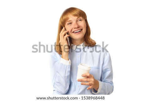 Young redheaded girl talking on her phone smiling and holding a cup of coffee