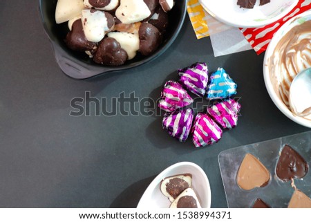 Preparations for making homemade chocolates. Heart shaped sweet homemade chocolate candies warped in colorful paper for the occasion of Diwali/Christmas/Valentines day. copy space for greetings.