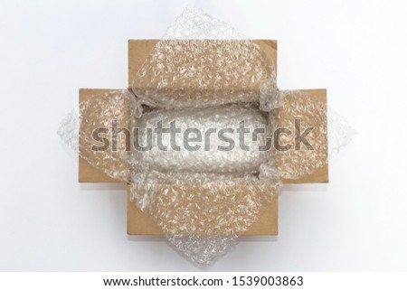 Plastic air bubble wrapped items in a brown cardboard box, ready to be shipped. Royalty-Free Stock Photo #1539003863