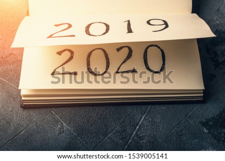 Notepad or calendar with pages and text 2020 and 2019 in sunlight. New year, new beginnings and change concept, toned