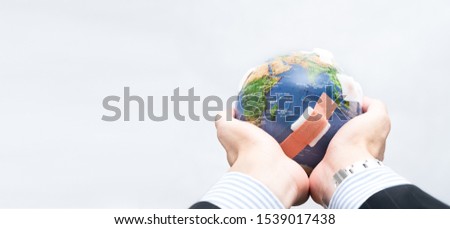 Closeup of an investor business man's hand holding a beautiful but damaged globe showing the concept of the industrial revolution impacted the global environment. Fossil fuel, Air pollution problems. Royalty-Free Stock Photo #1539017438