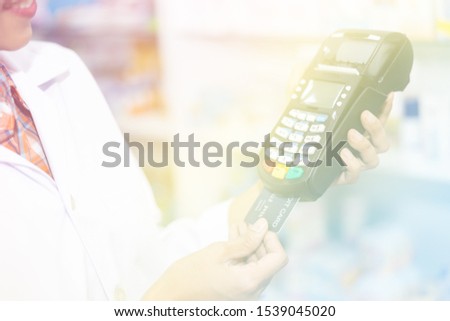 credit card machine on holding hand female pharmacist in pharmacy store Thailand pastel picture style process