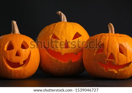 Pumpkins with scary faces on black background. Halloween traditional decor