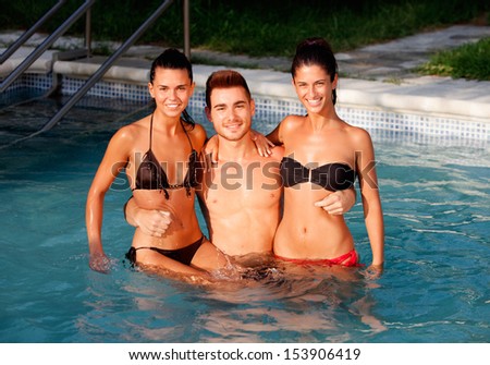 Three happy friends in the pool with a blue water of background