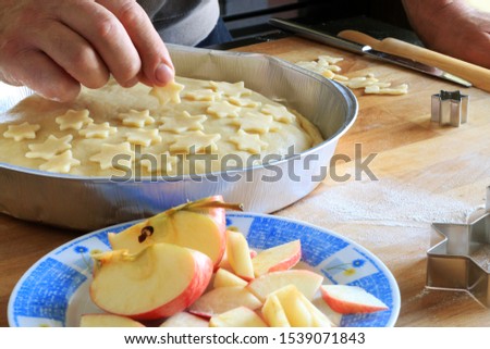 Traditional American homemade Christmas pie. Closeup of man's hands decorating an apple pie dessert with small shortcrust pastry stars
