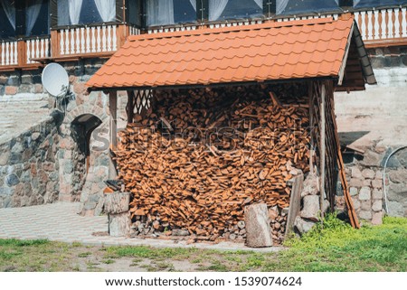 firewood stacked under roof in a wooden canopy. firewood for winter, dry chopped pile of firewood. wall of fire wood background.