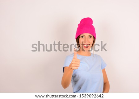 cute beautiful woman in pink hat smiles shows thumb up ok signs
