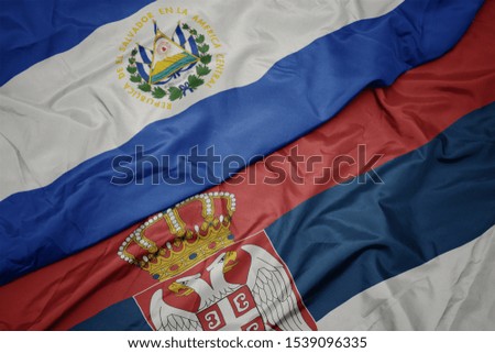 waving colorful flag of serbia and national flag of el salvador. macro