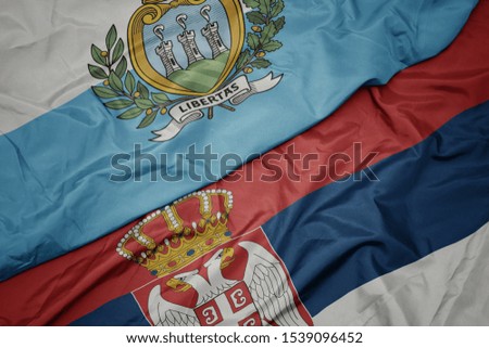 waving colorful flag of serbia and national flag of san marino. macro