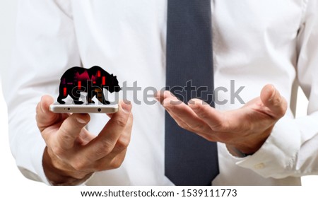 Silhouette of trading bear on the smatrphone screen in human hand.