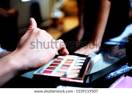 hand of makeup artist is choosing color from eyeshadow palette